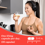 Woman holding a glass of water and a supplement capsule in a kitchen setting
